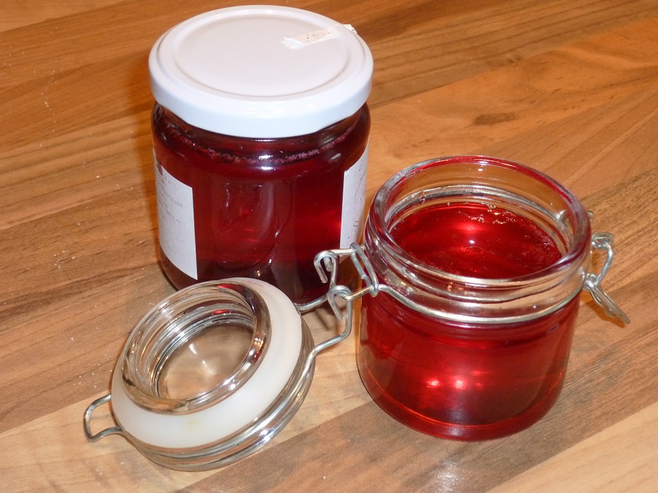 Two jars of homemade blackberry jelly from J&M’s Nursery, placed on a rustic wooden table